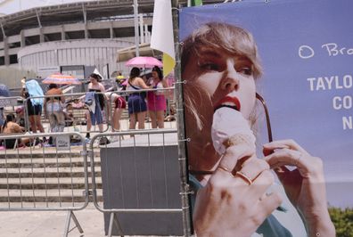 Taylor Swift fans wait for the doors of Nilton Santos Olympic stadium to open for her Eras Tour concert amid a heat wave in Rio de Janeiro, Brazil, Saturday, Nov. 18, 2023. A 23-year-old Taylor Swift fan died at the singer's Eras Tour concert in Rio de Janeiro Friday night, according to a statement from the show's organizers in Brazil.  (AP Photo/Silvia Izquierdo)