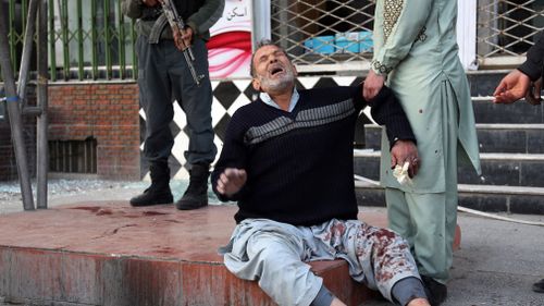 A relative of a victim is helped as he cries after a deadly suicide attack in Kabul, Afghanistan. (AAP)