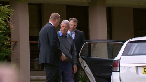 Homicide detectives lead Mr Spedding to their car outside his Bonny Hills home. (9NEWS)