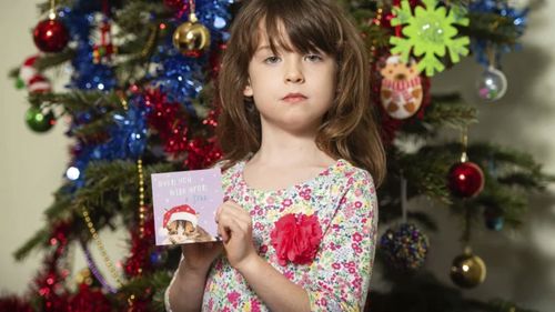 Florence Widdicombe, 6, poses with a Tesco Christmas card from the same pack as a card she found containing a message from a Chinese prisoner.