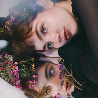 Woman lying on mirror, woman looking in the mirror, flowers