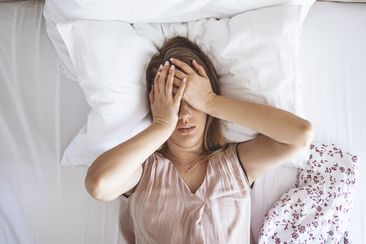 woman on bed having headache / insomnia / migraine / stress. 