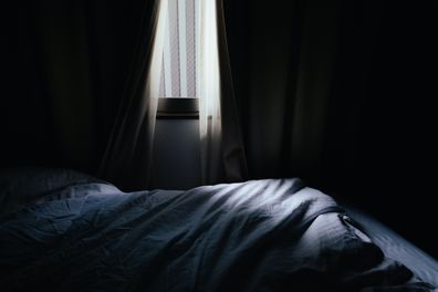 Image of a bedroom where light shines through the gaps in the curtains