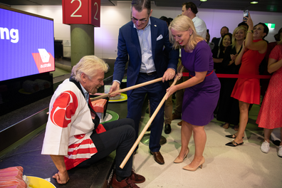 Staff help Sir Richard Branson up off the conveyor belt with oversized chopsticks.