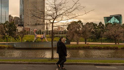 People wearing masks walk along the banks of the Yarra River on August 06, 2020 in Melbourne, Australia.