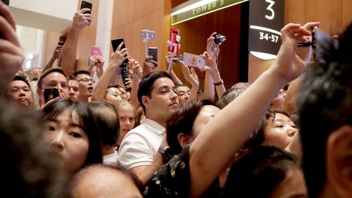 Some of the crowds of tourists and locals taking photographs of North Korean leader Kim Jong-un as he visit the Marina Bay Sands during a city tour. (AAP)