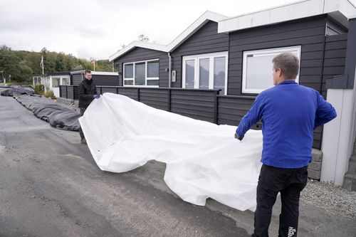 Jacob Nissen and Christian Mikkelsen, right, secure their summer house at Sonderballe Strand near Haderslev southern, Denmark Thursday, Oct. 19, 2023. 