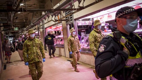 Members of Victoria Police aided by ADF soldiers patrol the Queen Victoria Market. 