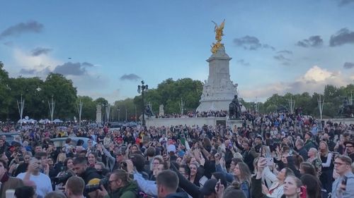 Crowd outside Buckingham Palace sing "God Save the Queen".