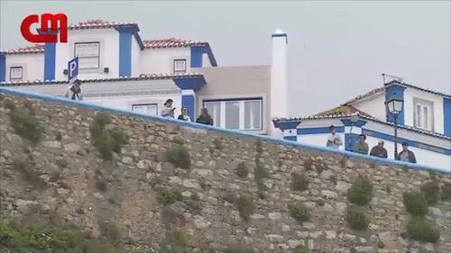 Emergency workers found a phone believe the couple may have been taking a selfie, before losing balance and falling. The large stone wall sits 30m above the popular surf beach. (Image: Correio Da Manha)