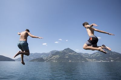 Young men jump into Lake Lucerne in Beckenried, Canton Nidwalden, Switzerland, against a spectacular backdrop.
