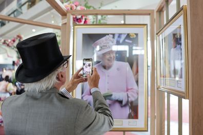 A racegoer takes a photo of the photographic exhibition curated by royal photographer Chris Jackson for Royal Ascot supported by Howden, to mark the late Queen's close association with Royal Ascot and a lifelong interest in horses and racing at Ascot Racecourse on June 20, 2023 in Ascot, England. 