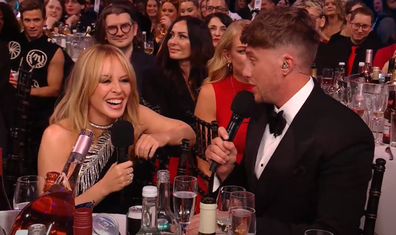 Kylie Minogue and Roman Kemp do a shoey during the 2024 Brit Awards