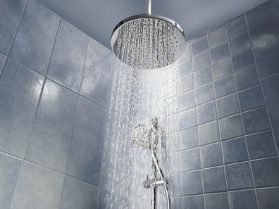 Low angle of running water from shower head in a cool coloured shower.