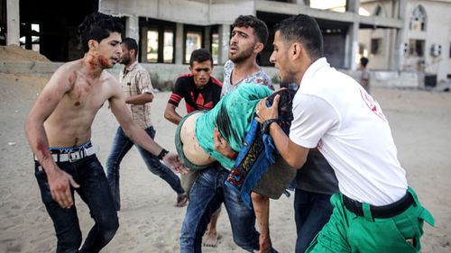 People carry the body of a Palestinian who was killed in an Israeli air strike, at central Gaza City, 14 July 2018. (AAP)