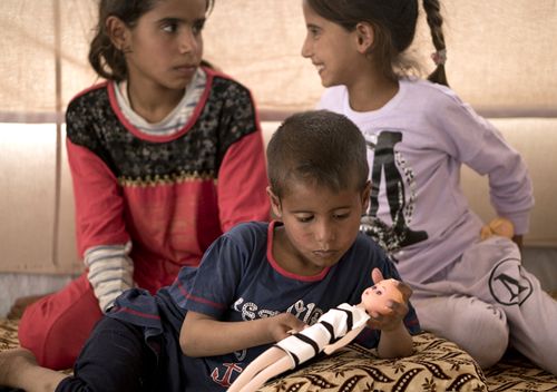  Dawoud Suleiman plays with a doll as his sisters Dawlat, left, and Omaima, sit with him in their tent at Dakuk Camp, near Kirkuk, Iraq. Traumatized by a series of tragedies suffered during three years of fighting in Iraq, the children live under an additional burden: Their father and other family members belonged to the Islamic State group. 