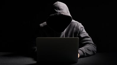 Hacker scammer dark hooded laptop computer