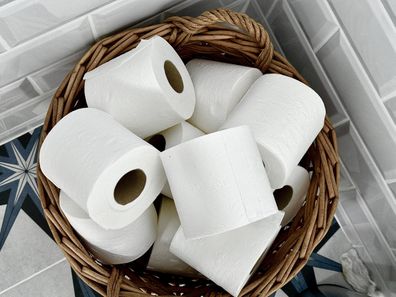 Directly above a wicker basket containing toilet rolls in a domestic bathroom