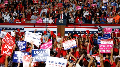 Supporters waves signs as President Donald Trump speaks at a rally in Pensacola.