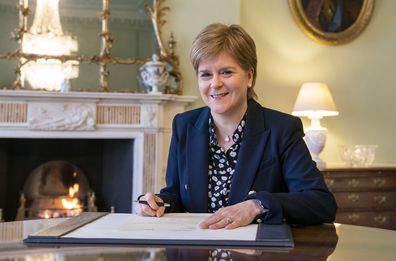 Outgoing First Minister of Scotland Nicola Sturgeon smiles as she signs her official resignation letter to Britain's King Charles III in the Drawing Room at Bute House in Edinburgh, Scotland, Tuesday March 28, 2023. 