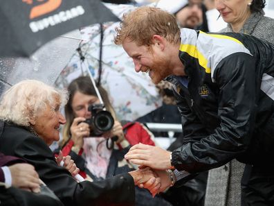Prince Harry hugs 97-year-old Daphne Dunne while walking in torrential rain ahead of an Invictus Games Launch Event in Sydney 2018 in 2017