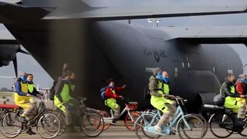 Protestors ride bicycles around aircraft, preventing them from leaving.