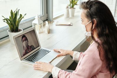 Woman in face mask on computer