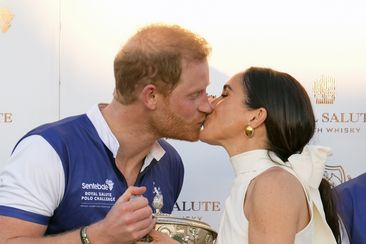 Prince Harry and Meghan Markle, Duchess of Sussex, kiss as she presents his polo team with the trophy for winning the Royal Salute Polo Challenge to Benefit Sentebale, Friday, April 12, 2024, in Wellington, Florida