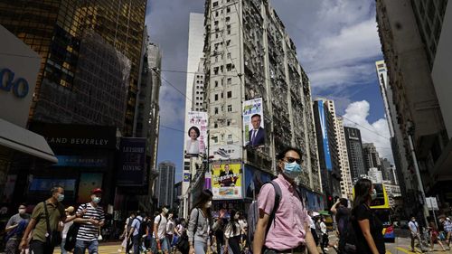 People wearing face masks walk on a downtown street in Hong Kong.