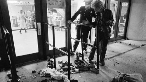 A security guard and an unidentified man look at an area with shows and clothes strewn around where several people were killed and others injured, as they were caught in a surging crowd entering Cincinnati's Riverfront Coliseum for a Who concert on December 3, 1979. 