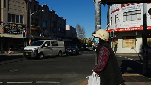 A woman on Marrickville a road waits to cross over Illawarra Road in Marrickville during the COVID-19 lockdown. 