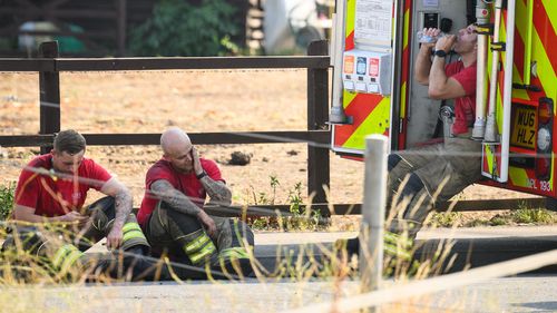 Members of the fire services rest after tackling a huge blaze in a residential area on July 19, 2022 in Wennington, England. (Photo by Leon Neal/Getty Images)