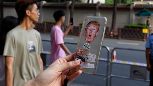 A resident holds up a phone cover depicting US President Donald Trump for a photo outside the United States Consulate in Chengdu in southwest China's Sichuan province