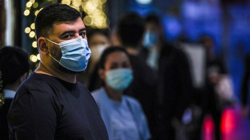 People in Sydney wear face masks as they stand in a line inside a shopping centre. Some LGAs in Sydney remain 'red-zoned' by Victoria.