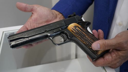 Brian Witherell displays a Colt .45-caliber pistol that once belonged to mob boss Al Capone, at Witherell's Auction House in Sacramento, Calif., Wednesday, Aug. 25, 2021. The pistol is among the 174 family heirlooms that will be up for sale at an Oct. 8 auction titled "A Century of Notoriety: The Estate of Al Capone," that will be held by Witherell's.  (AP Photo/Rich Pedroncelli)