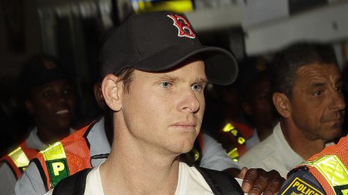 Smith was surrounded by security and heckled as he left Johannesburg to fly home. (AAP)
