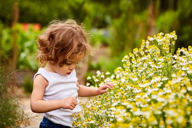 Young girl playing outside in garden. toddler playing outside.