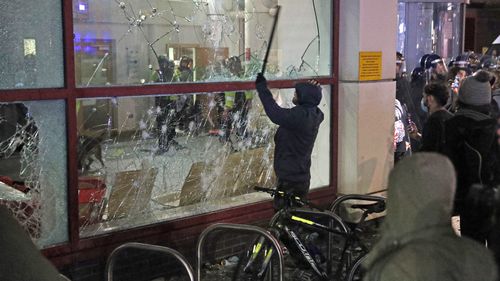 A person breaks a window with a stick outside Bridewell Police Station, in Bristol