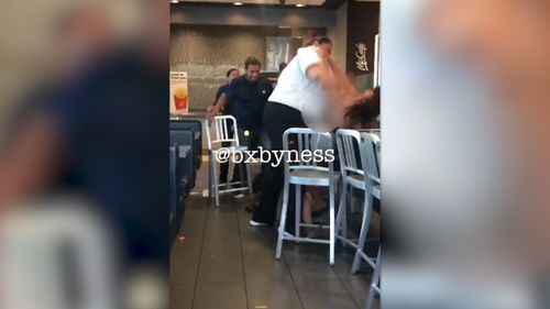 A woman in a McDonald's uniform storms into view and the customer manages to get in a pre-emptive strike with a tray before the pair tussle. Picture: Facebook/Marie Dayag
