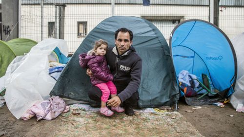 A father with his daughter at a makeshift refugee camp north of Paris in 2015. 