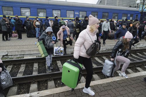 People gather to catch a train and leave Ukraine for neighboring countries at the railway station in Lviv,western Ukraine, Saturday, Feb. 26, 2022. The U.N. refugee agency says nearly 120,000 people have so far fled Ukraine into neighboring countries in the wake of the Russian invasion. The number was going up fast as Ukrainians grabbed their belongings and rushed to escape from a deadly Russian onslaught. (AP Photo/Mykola Tys)