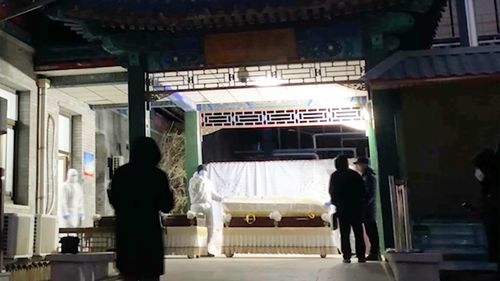 Workers move caskets at a funeral complex in Beijing, Friday, Dec. 16, 2022. 