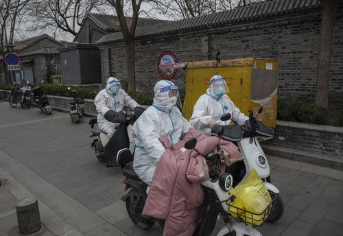 BEIJING, CHINA - MARCH 25: Health workers wear protective suits as they ride scooters in a traditional courtyard neighborhood where they were performing nucleic acid tests to detect COVID-19 on local residents on March 25, 2022 in Beijing, China. China has stepped up efforts to control a recent surge in coronavirus cases across the country, locking down the entire province of Jilin and the city of Shenyang and putting others like Shenzhen and Shanghai under restrictions. Local authorities across