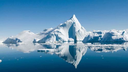 Icebergs drift in calm seas off the Greenland coast.