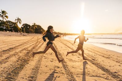 Children running on the beach towards the ocean in Noosa
