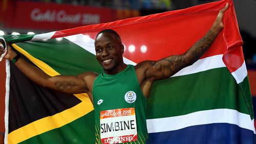 Akani Simbine holds the South African flag after winning the 100m. (AAP)