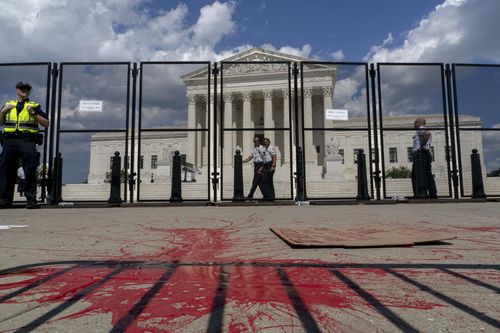 Red painting covers part of the sidewalk outside the Supreme Court as people protest about abortion in Washington.