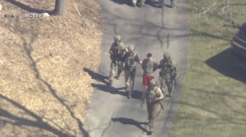 This image made from video provided by WCVB-TV, shows Jack Teixeira, in T-shirt and shorts, being taken into custody by armed tactical agents on Thursday, April 13, 2023, in Dighton, Massachusetts 