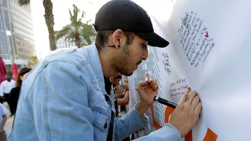 Norman Casiano, a survivor of the Pulse nightclub shooting, writes a note on a banner during a vigil in solidarity with the victims of the mass shooting in Las Vegas. (AP)