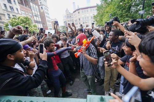 The crowd eggs on a person holding a toy gun wearing a spider man mask, Friday, Aug. 4, 2023, in New York's Union Square. 